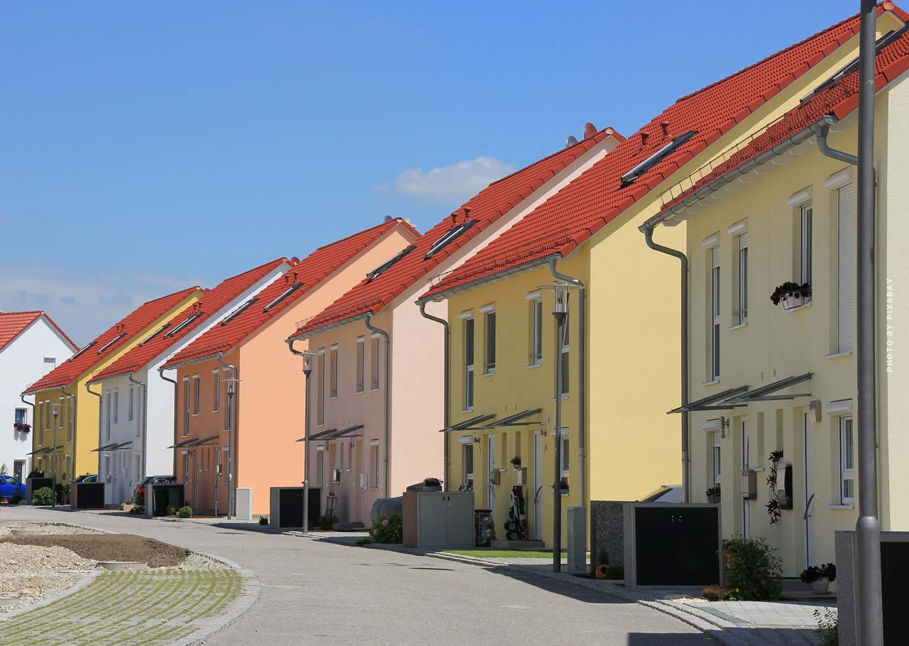 Hier sehen Sie eine typische Siedlung von Doppelhäusern mit bunter Fassade an einer Straße. 