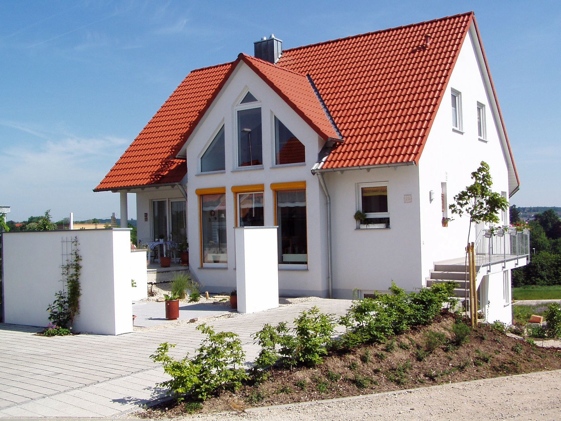 Weißes Einfamilienhaus mit Vorgarten.
