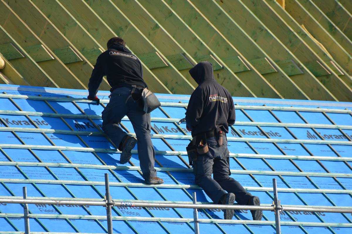 sanierung-moderniesierung-haus-wohnung-immobilie-dach-dachdecker-bedachung-empfehlungen-handwerker-giebel-manner-blau-gruen-arbeit