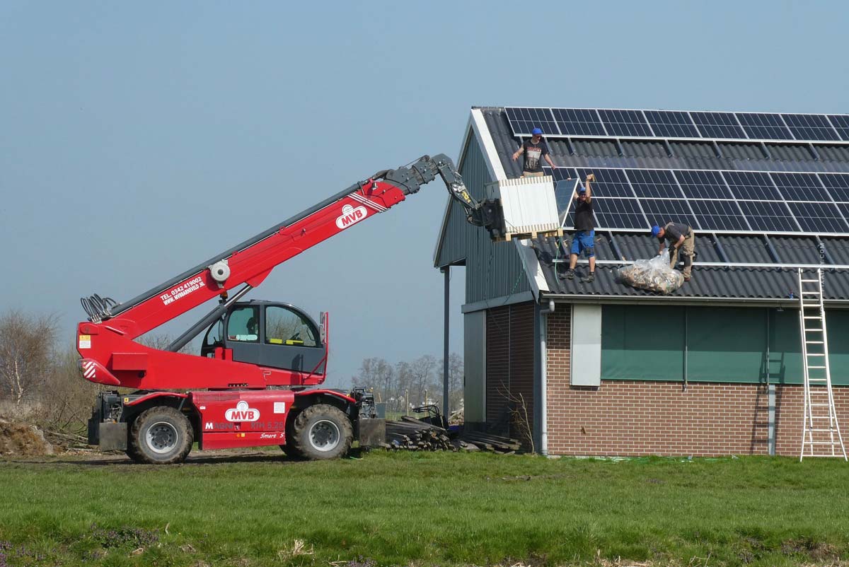 Auf diesem Bild werden Solarzellen mit Hilfe eines Krans auf einem Dach angebracht. 