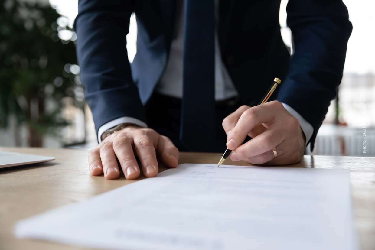 Vertragsunterzeichnung Kaufvertrag: Unterschrift auf Papier, Mann mit Anzug