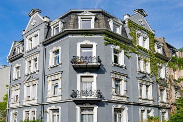 mietverwaltung-hausverwaltung-definition-aufgaben-arten-vertrag-kosten-ratgeber-tipps-mehrfamilienhaus-altbau-fassade-blau-balkon-fenster-himmel-705×470