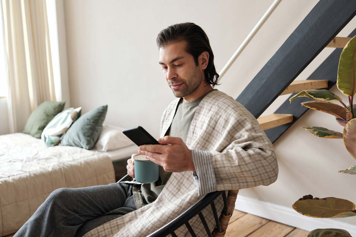 mann-zuhause-lange-haar-smartphone-lernen-immobilien-investor-kapitalanlage-nebenberuflich-neben-dem-beruf-online